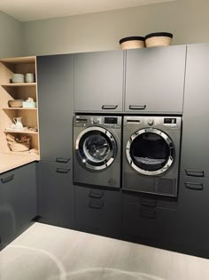 a washer and dryer in a room with shelves on the wall behind them