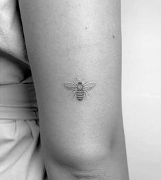 a black and white photo of a bee tattoo on the right side of the thigh