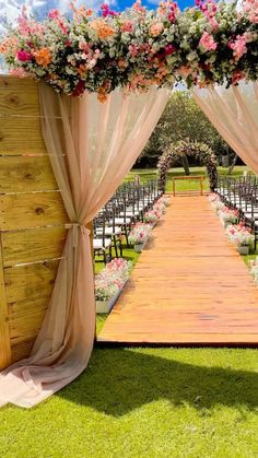 an outdoor ceremony set up with chairs and flowers on the aisle, in front of a wooden