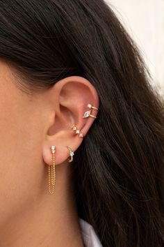 a woman wearing gold ear cuffs with white stones on the top and bottom of her ears