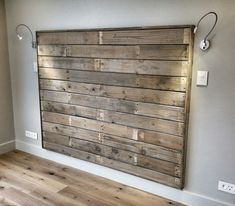 a wooden wall mounted to the side of a white wall in an empty room with wood flooring