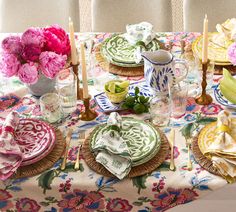 a table set with plates, napkins and flowers