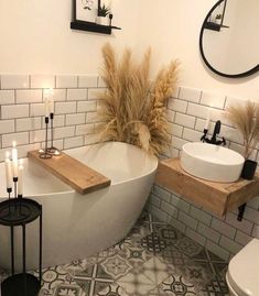 a white bath tub sitting next to a toilet under a bathroom mirror on top of a wooden shelf