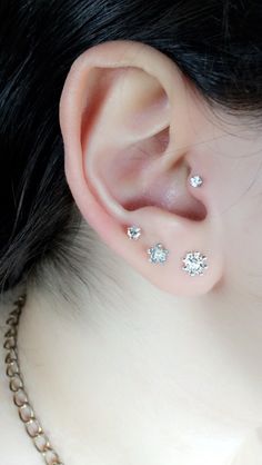 a close up of a person's ear with three piercings