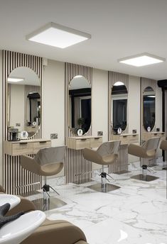 a salon with chairs, mirrors and sinks on the walls in front of them is white marble