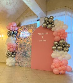 an arch made out of balloons in the middle of a room with a sign on it