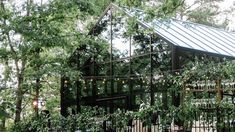 the house is surrounded by trees and greenery with lights hanging from it's roof