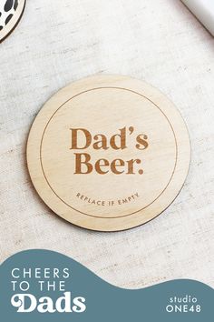 a wooden coaster with the words dad's beer on it next to other items