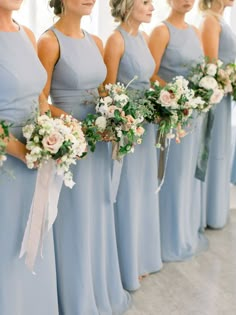 the bridesmaids are all wearing blue dresses and holding bouquets