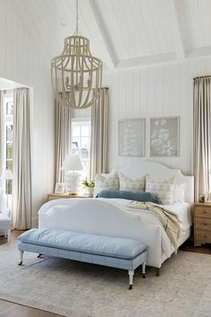 a bedroom with white walls and wood flooring has a large bed in the center