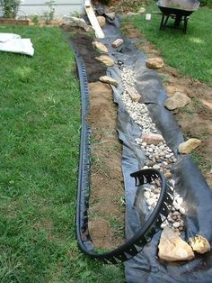 a garden hose laying on top of some rocks and gravel next to a fenced in area