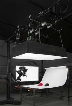 a photo studio setup with lighting equipment and lights on the ceiling, in front of a black background