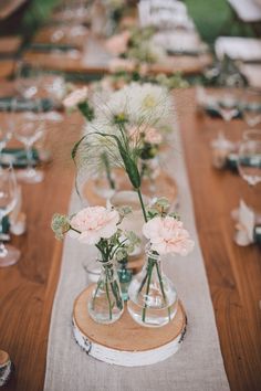 there are many vases with flowers in them on the long wooden table cloth runner