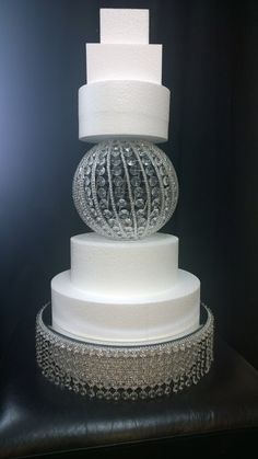 a three tiered wedding cake with white frosting and crystal beads on the top