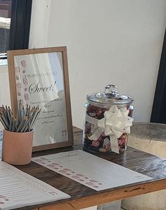 an open notebook sitting on top of a wooden table next to a potted plant