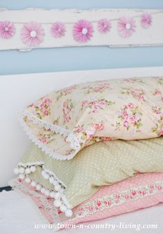 four pillows stacked on top of each other in front of a white headboard with pink flowers