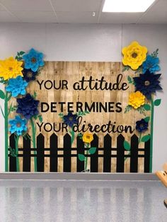 a wooden sign that says your attitude determines your direction with flowers on the fence behind it