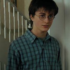 a young man wearing glasses standing next to a stair case