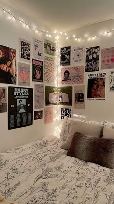 a bed with lots of posters on the wall above it and lights hanging from the ceiling