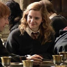 two young women sitting at a table with cups and saucers in front of them