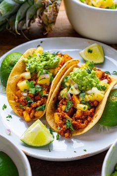 two tacos are sitting on a plate next to limes and pineapples