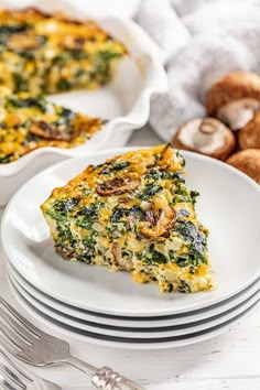 a slice of quiche with spinach and mushrooms on a white plate next to silverware