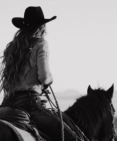 a black and white photo of a woman riding on the back of a brown horse