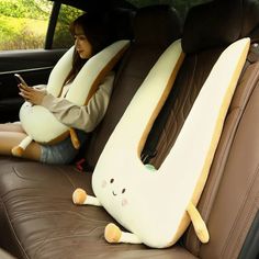 a woman sitting in the back seat of a car holding a cell phone and stuffed animal