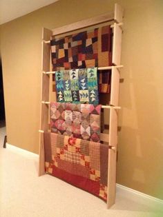 a wooden shelf with quilts on it in a room next to a wall and carpet