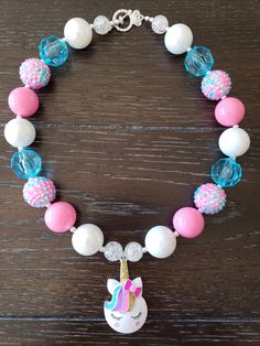 "Unicorn Inspired Chunky Bubblegum Bead Children's Necklace This Unicorn themed necklace will bring a smile to your little one's face! This will make a lovely party favor or gift for birthdays or just as an everyday accessory. Made with primarily 20mm bubblegum beads in shades of blue, pink, blue and white. The necklace measures approximately 11\" when toggled around neck including the unicorn pendant. The bracelet is made with elastic and doubled up for strength. This necklace is great for all Cute Round Beads Jewelry For Party Favors, Playful Colorful Beads Necklaces For Birthday, Playful Colorful Beads Necklace For Birthday, Fun Pink Necklace For Birthday, Pink Novelty Necklace For Birthday, Novelty Beaded Jewelry For Birthdays, Novelty Pink Necklace For Birthday, Fun Adjustable Beaded Necklace For Birthday, Fun Adjustable Beaded Necklaces For Birthday