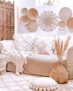 a living room filled with white furniture and lots of plates on the wall above it