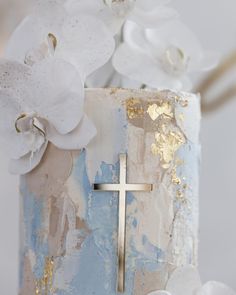 a cake decorated with white flowers and a cross on the top is sitting on a table