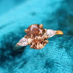 an orange diamond ring sitting on top of a blue cloth