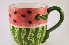 a watermelon painted coffee cup sitting on top of a table