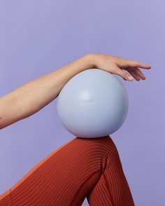 a woman's hand on top of an exercise ball in front of a purple background