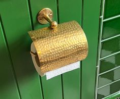 a gold toilet paper holder on a green wall