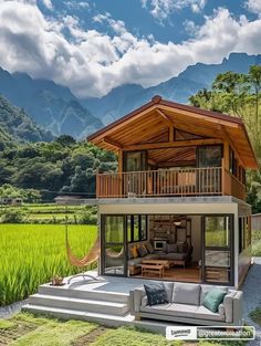 a small house sitting in the middle of a lush green field with mountains in the background