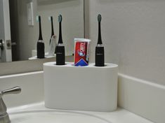 "Electric Toothbrush Holder for AquaSonic, with Toothpaste Storage 3D Printed, Plastic Storage unit to place next to sink, or on bathroom counter to hold a pair of AquaSonic electric toothbrushes (and their chargers), and a standard tube of toothpaste. This helps keep bathroom organized and declutters counterspace. Intended for AquaSonic Black and Vibe Series (if using charger port). May fit additional models or brands, please reference sizing below to confirm. Sleek, slim design offered in mult Bathroom Organization Electric Toothbrush, Bathroom Electric Toothbrush Storage, Sonicare Toothbrush Storage, Electronic Toothbrush Storage, Hide Electric Toothbrush On Counter, Electric Toothbrush Holder Ideas, Toothpaste Storage Ideas, Hiding Toothbrushes Bathroom, Hide Electric Toothbrush