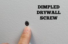 a finger pointing at a hole in the wall that says dimpled drywall screw