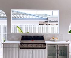 an outdoor kitchen with stainless steel appliances and white tile counter tops, along with potted plants