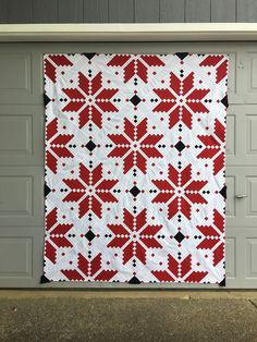 a red and white quilt hanging from the side of a garage door