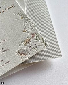 two wedding cards with flowers on them are laying next to each other in front of a white background