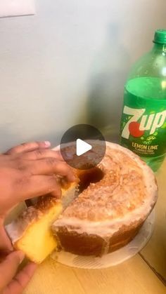 a person is holding a piece of bread with cheese on it next to a bottle of soda