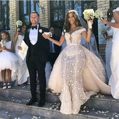 the bride and groom are walking down the steps together in their wedding gowns,