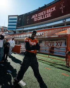 a man in an orange and black uniform standing on the field with his arms crossed