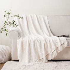 a white couch sitting on top of a wooden floor next to a rug covered in a blanket