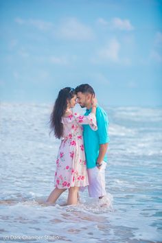 a man and woman standing in the water at the beach with their arms around each other