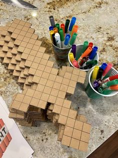 a table topped with cups filled with markers and pencils on top of a counter