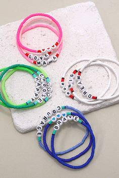 four bracelets with words on them sitting on a white surface next to each other