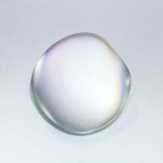 a close up of a white object on a white surface with only one drop in the middle